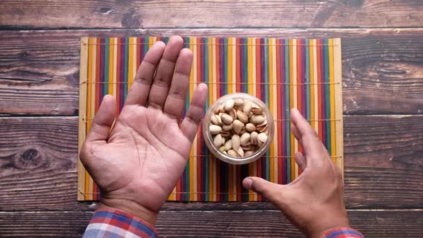 Mano de hombre sosteniendo un tazón de pistachos nuez — Vídeo de stock