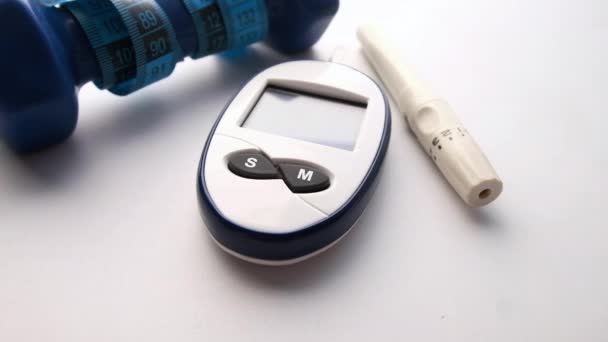 Blood glucose meters and dumbbell on white background — Stock Video