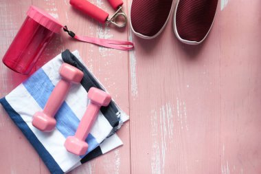 Pembe arka planda dambıl, ayakkabı ve su şişesinin üst görüntüsü 