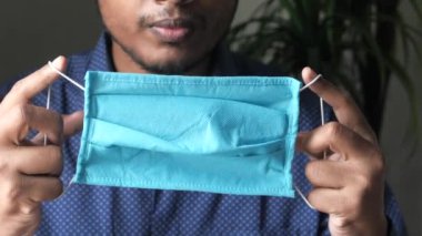 Kauçuk kulaklıklı cerrahi maske takan adamların ellerini kapatın. 