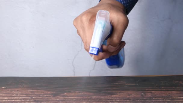 Χέρι κρατώντας μπουκάλι ψεκασμού καθαρισμού ένα τραπέζι — Αρχείο Βίντεο