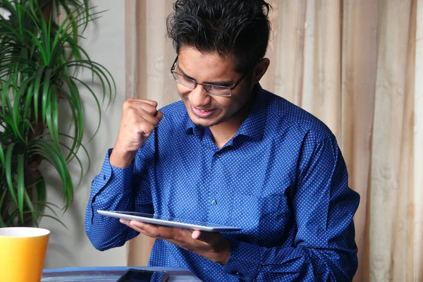 Gelukkige jongeman werkt aan digitale tablet op kantoor bureau, — Stockfoto