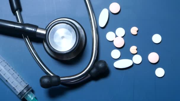 Piller, stetoskop och spruta på blå bakgrund — Stockvideo