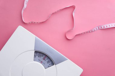 Pembe arka planda bir mezura ve banyo ölçeği 