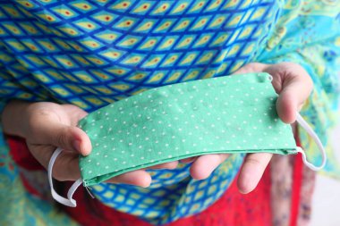 El ele tutuşan renkli ev yapımı koruyucu maske.