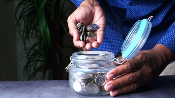 Close up of man saving coins in a jar — Stock video