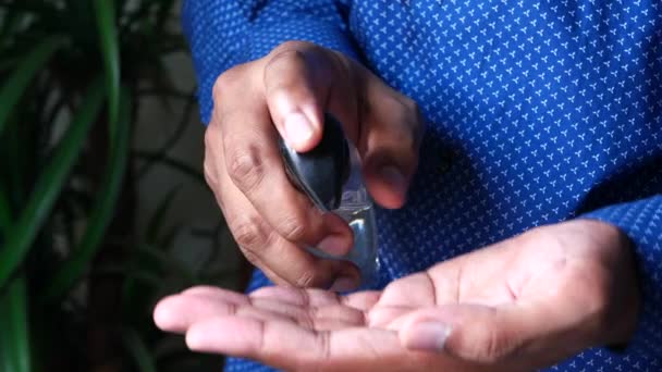 Młody człowiek w niebieskiej koszuli za pomocą żel do dezynfekcji rąk, — Wideo stockowe