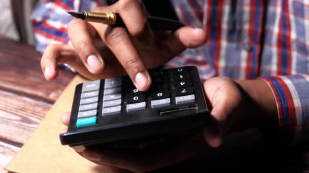 Gros plan de la main de l'homme en utilisant la calculatrice sur le bureau — Video