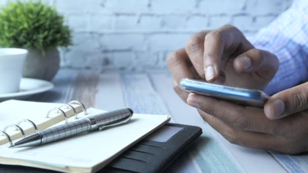 Hombre usando el teléfono inteligente móvil en el escritorio de la oficina — Vídeos de Stock