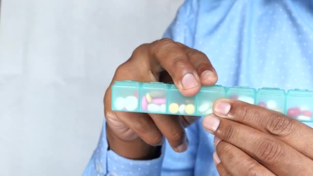 Young man taking pill from pill box — Stockvideo