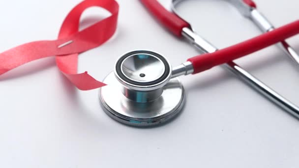 Červená stuha HIV, a stetoskop na bílém pozadí. — Stock video