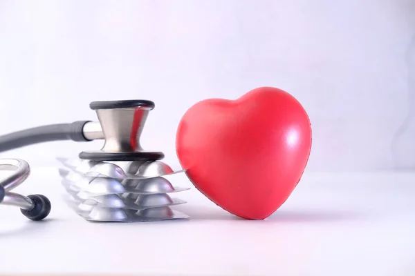 red heart. pills and stethoscope on white background