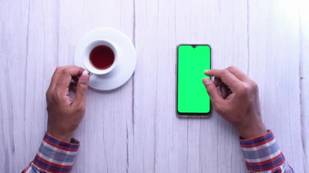 Muž ruka pomocí chytrý telefon se zelenou obrazovkou na dřevěném stole — Stock video