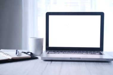 Ofis masasında beyaz kahve fincanı olan boş ekranlı dizüstü bilgisayar. 