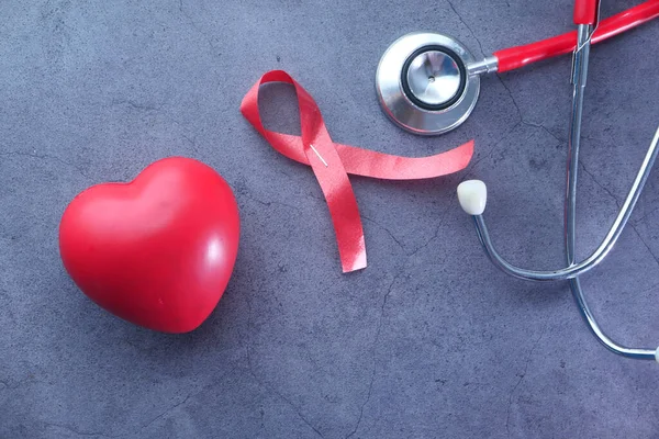 Red ribbon HIV, heart and stethoscope on black background. — Stock Photo, Image