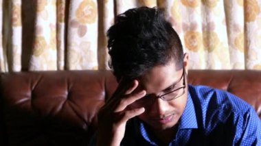 Hüsrana uğramış genç adam koltukta oturuyor. 