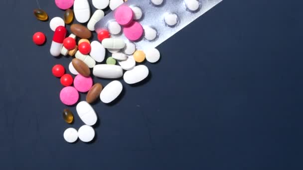 Colorful pills spilling on dark background top down — Stock Video