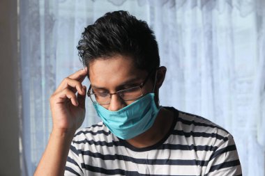 Enfeksiyonu önlemek için hijyenik maske takan genç adam.