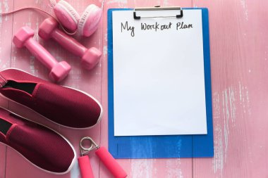 Antrenman planı konsepti dambıl, ayakkabı ve su şişesi pembe arka plan 