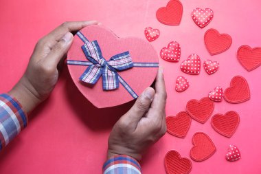 Elinde küçük kırmızı bir kutu tutan bir adam var..