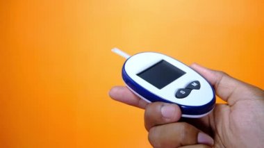 Turuncu arka planda kan şekeri ölçerler. 