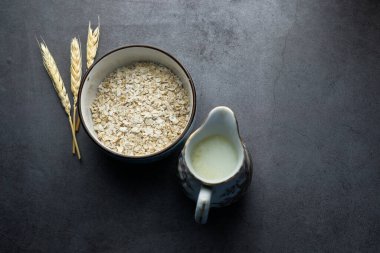 Siyah arkaplanda pişmemiş yulaf gevreği ve sütün yüksek açılı görüntüsü 