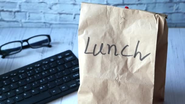Bolsa de almuerzo de papel en el escritorio de la oficina, primer plano . — Vídeos de Stock