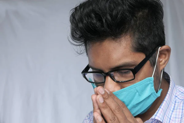 Un giovane asiatico uomo maschera sul suo viso pregando — Foto Stock