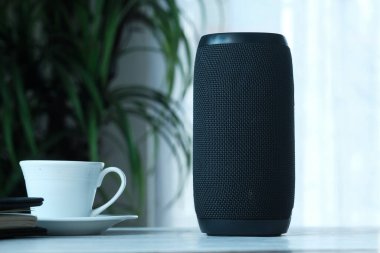 Akıllı hoparlör ve çay fincanı ahşap masada 