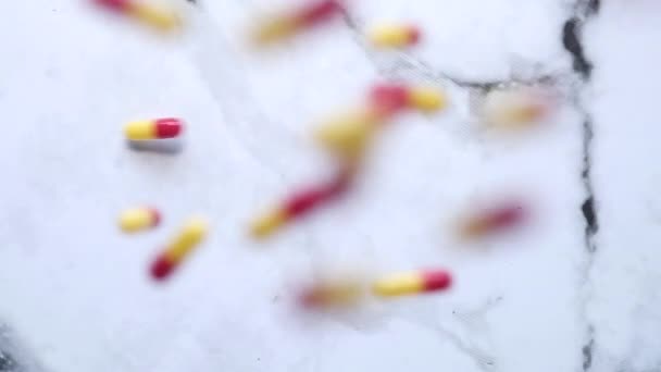 Повільний рух барвистих капсул падає на фоні плиток — стокове відео