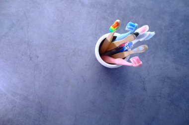  Beyaz fincanda gri arkaplanda renkli diş fırçaları