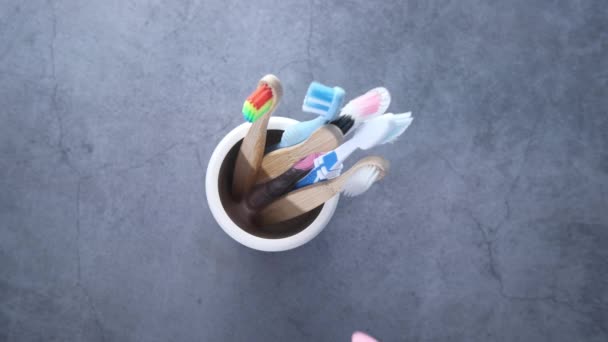 Kleurrijke tandenborstels in witte mok op grijze achtergrond — Stockvideo
