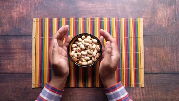 Bovenaanzicht van de mens hand nemen pistachenoten uit een kom — Stockvideo