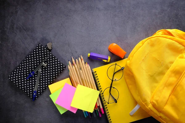 Vue du dessus du sac à dos jaune avec différentes papeterie colorée sur la table. — Photo