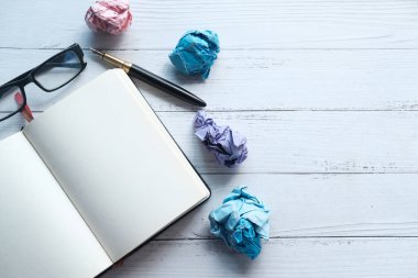 Buruşmuş kağıt top ve not defteri ahşap masanın üzerinde..