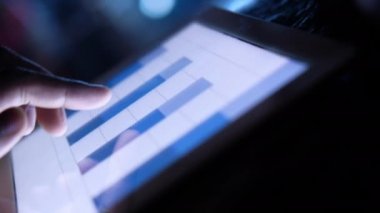 Adam el ile ofis masasında dijital tablet üzerinde çalışıyor, kendi yarattığı grafiği kullanarak. 