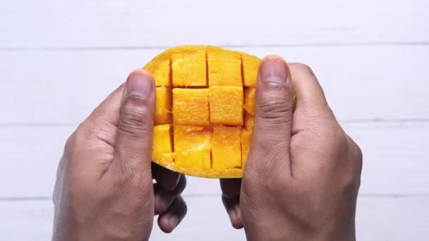 Man eet gele rijpe gesneden mango naar beneden — Stockvideo