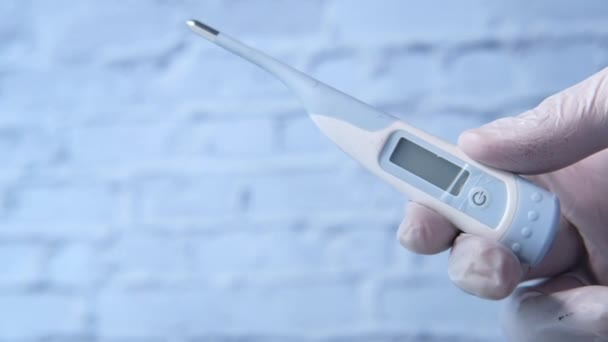 Mann Arzt in weißem Medizinhandschuh hält digitales Thermometer in der Hand — Stockvideo