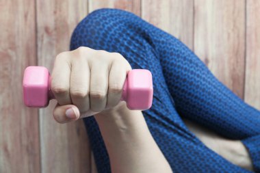 Dambıl ağırlığıyla egzersiz yapan genç bir kadın. 