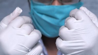 Yüz maskeli doktor tıbbi eldiven gösteriyor. 