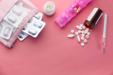 Beyaz haplar, su toplaması, hap kutusu ve pembe arka planda termometre. 