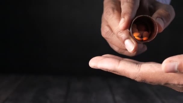 Close-up van de man hand het nemen van pillen geïsoleerd in zwart — Stockvideo