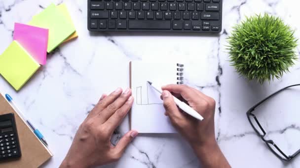 Man tekening staafdiagram op notitieblok top naar beneden — Stockvideo