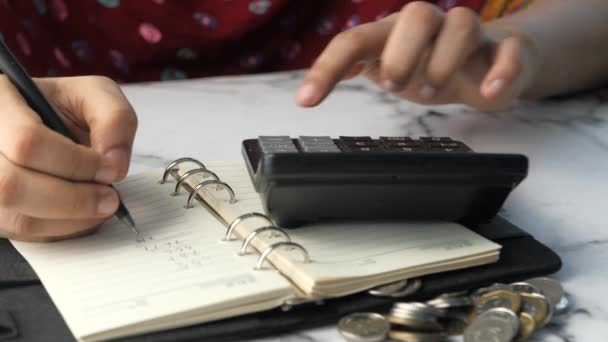Fechar a mão das mulheres usando calculadora e escrita no bloco de notas — Vídeo de Stock
