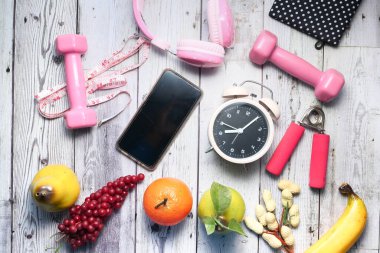 Ahşap arka planda egzersiz aletleri ile sağlıklı fitness ve meyve konsepti.