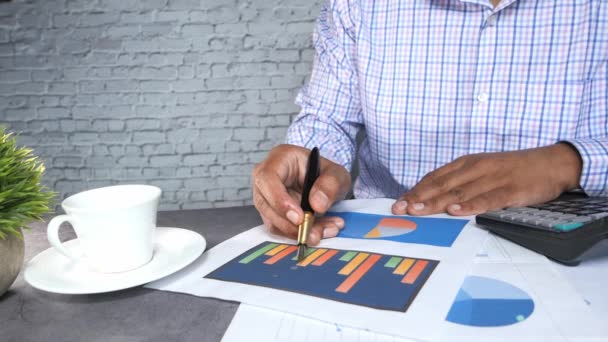 Geschäftsmann Hand mit Stift analysiert Finanzdiagramm auf Papier — Stockvideo