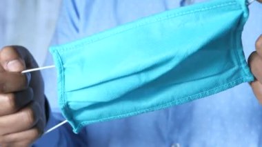 Ellerinde cerrahi maske tutan genç adama yaklaş. 