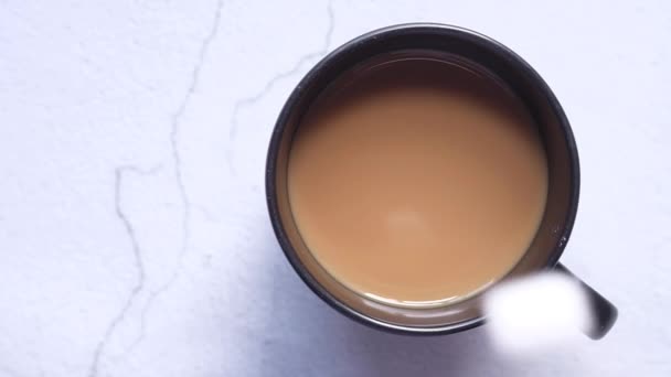 Pohled shora na kostku cukru padající do šálku kávy. — Stock video