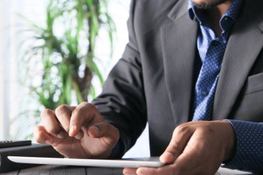 Adam el ile ofis masasında dijital tablet üzerinde çalışıyor, kendi yarattığı grafiği kullanarak. 