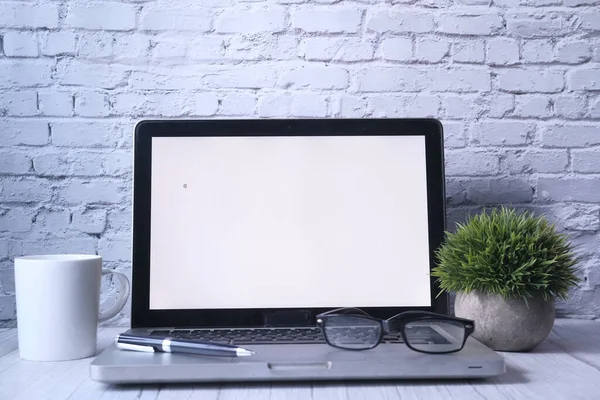 Espacio de trabajo con portátil con maqueta de pantalla blanca en blanco . — Foto de Stock